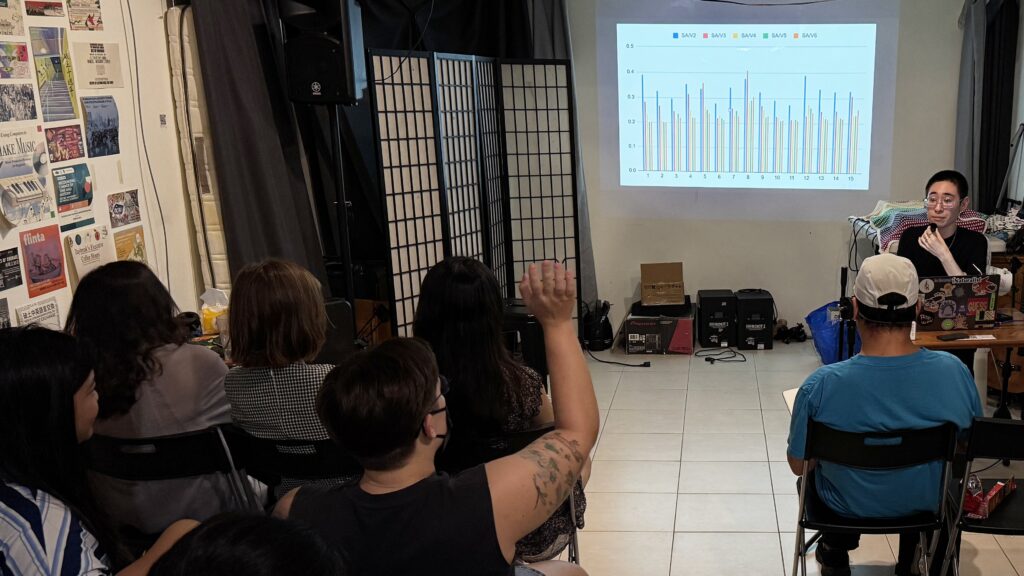 Photo of River Basham answer an audience member's raised hand, in front of a slide with bar graphs
